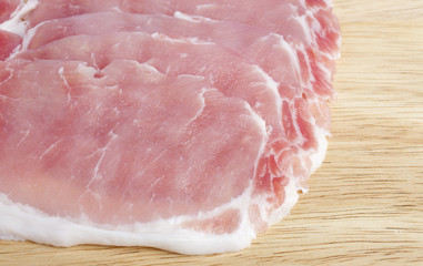 Several rashers of bacon on wooden chopping block
