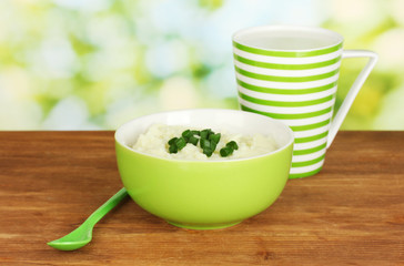 Mashed potato in the bowl and cup with milk on wooden