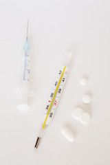 Clinical thermometer, syringe and white pills