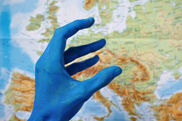 Eine blaue Hand formt das Euro-Symbol vor einer Europakarte.