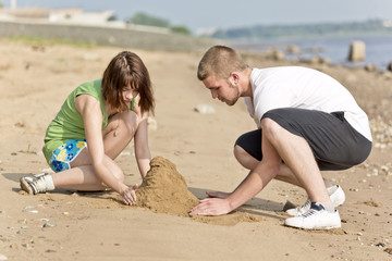 Fototapeta premium The guy and the girl fill a heap of sand