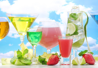 Glasses of cocktails on table on blue sky background
