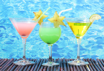 Glasses of cocktails on table on blue sea background