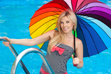 beautiful girl by the pool with colored umbrella
