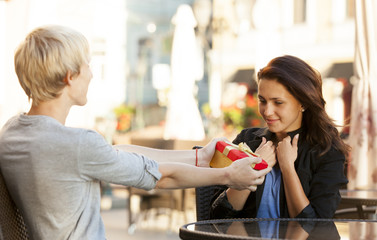 The young man gives a gift to a young girl in the cafe