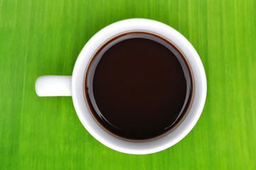 a cup of black coffee on banana leaf