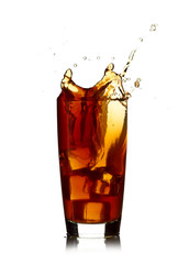 Ice cube droped in cola glass and cola splashing