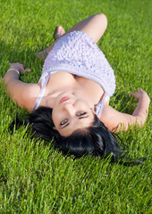 Beautiful girl lying on her back in lawn.