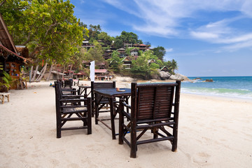 Chairs and table on the sand beach with blue sky