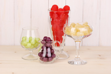 Color candies in glasses on wooden background