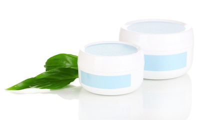 Jars of cream with green leaves isolated on white