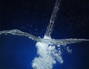 Naklejka na ściany i meble Pouring water. Splash image on a blue background