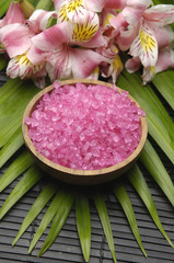 bowl of bath salt, orchid flower and palm leaf on brown mat