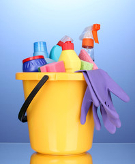 Bucket with cleaning items on blue background