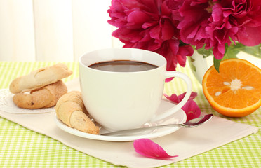 cup hot chocolate, cookies and flowers on table in cafe