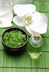 bath salt and white orchid with essential oil on green mat