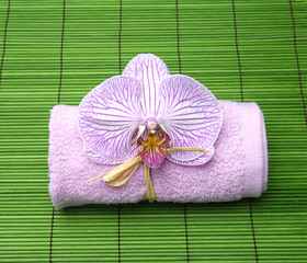 Pink orchid on towel on green stick straw mat
