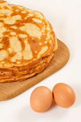 Pile of pancakes with some flour and eggs on white background