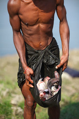 Fisherman with his catch of fish in longyi, Myanmar