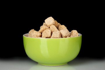 brown cane sugar cubes in bowl on black background