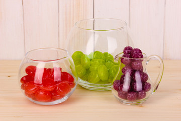 Color candies in glasses on wooden background
