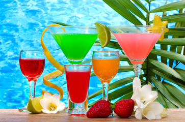 exotic cocktails and flowers on table on blue sea background