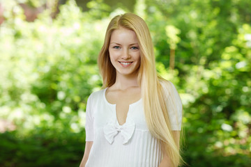 Naklejka na ściany i meble Closeup of young smiling woman on background of summer nature