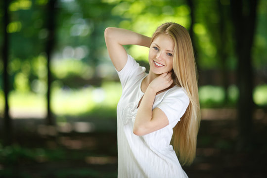 Beautiful smiling girl posing over green summer background