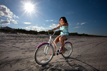 Fototapeta premium Young Brunette Woman riding bike on Beach
