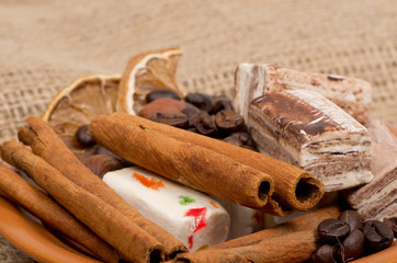 Sweets, cinnamon, nuts and coffee beans on a saucer, on burlap b