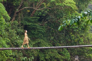 woman walking on jungle bridge