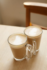 coffee latte in two tall glasses woden table and chair