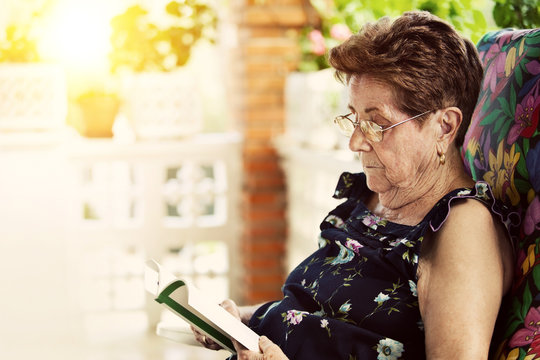 Elderly Woman Reading A Book In A Warm Evening