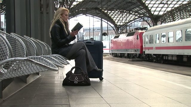 Business woman waiting and reading a book on central station