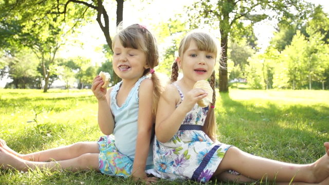 Girls eating ice cream. Sitting on the grass