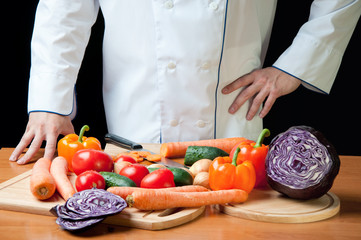 Chef standing by the table with variety of fresh vegetables