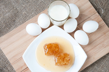 Fresh honey, glass of milk and eggs, view from above