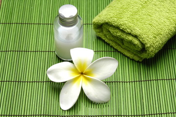 Obraz na płótnie Canvas frangipani flower and towel with massage oil on green mat