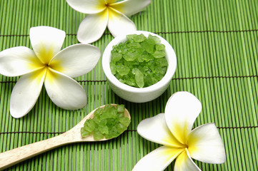 frangipani and Green salt in wooden spoon with bowl on green mat
