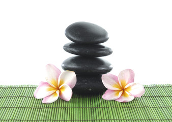 Fototapeta na wymiar Two frangipani flower and stacked stones on green mat