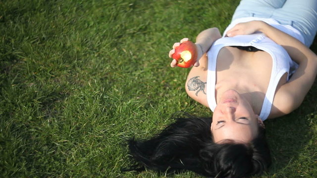 Woman eating an apple on the grass