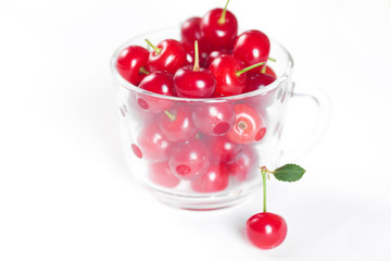 cherry with green leaf and a cup of cherries on a white backgrou
