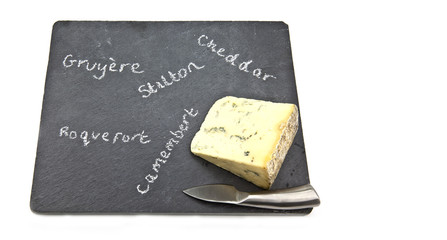 Stilton cheese on slate cheeseboard with knifewith wite backgrou