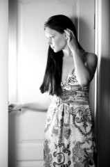 Young woman behind opened white door looking inside