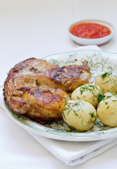 Roasted chicken and potato with vegetables on a white plate