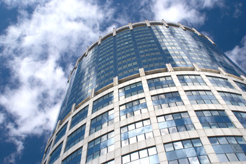 Fototapeta premium Modern office round tower building over sky with clouds