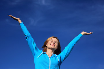 Woman with arms outstretched against blue sky