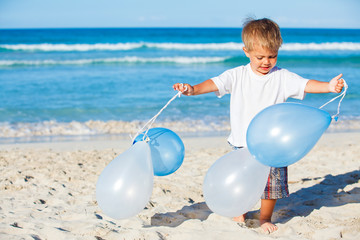 boy plays with ballons on the beach