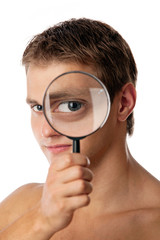 Cute young man looking through a magnifying glass