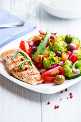 Grilled chicken fillet with fresh vegetables and olives